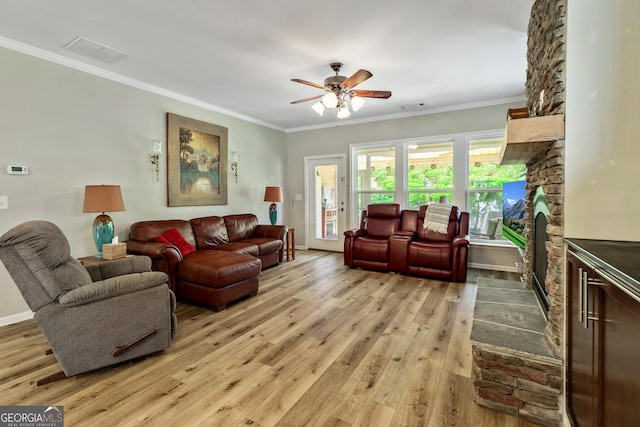 733 Firefly Ct, Griffin, GA 30223 - living area featuring light wood-style floors, a ceiling fan, a stone fireplace, crown molding, and baseboards