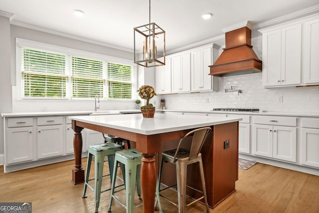 3298 Alcovy Club Ct, Dacula, GA 30019 - kitchen with custom range hood, a breakfast bar area, light countertops, a kitchen island, and decorative backsplash
