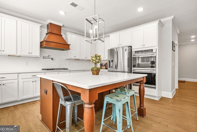 3298 Alcovy Club Ct, Dacula, GA 30019 - kitchen featuring appliances with stainless steel finishes, ornamental molding, custom exhaust hood, a breakfast bar, and decorative backsplash