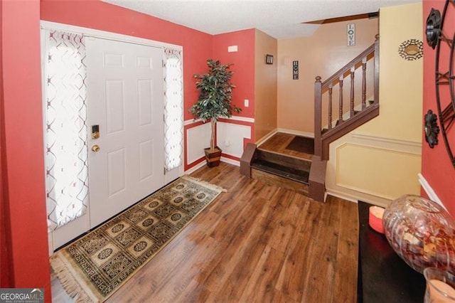 foyer entrance with wood finished floors, stairs, and baseboards