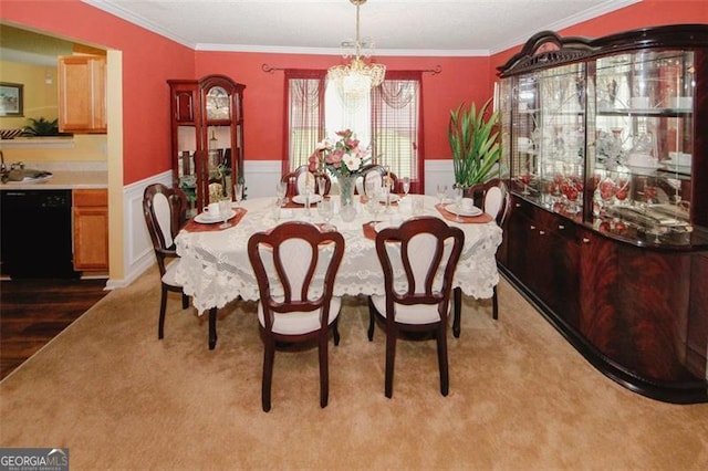 dining area featuring a wainscoted wall, a chandelier, crown molding, and carpet flooring