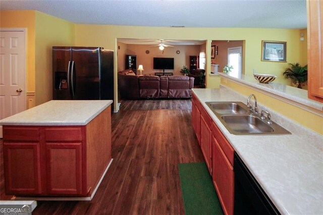 kitchen featuring black appliances, a sink, dark wood finished floors, and light countertops