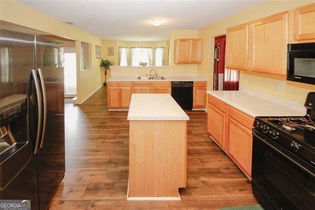 kitchen with black appliances, a sink, and light brown cabinetry