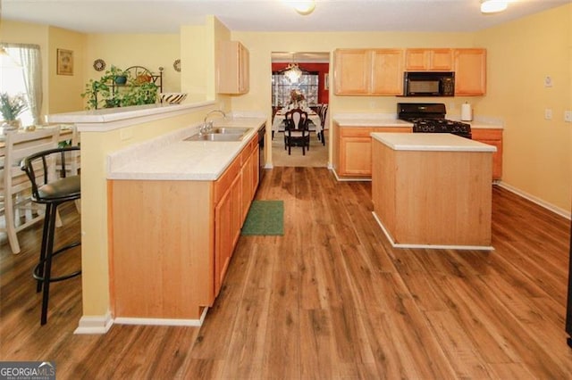 kitchen featuring black appliances, a sink, light countertops, and light brown cabinets