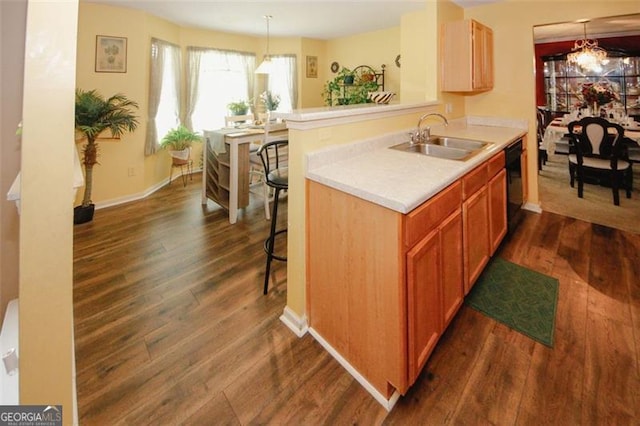 kitchen featuring a sink, black dishwasher, dark wood-style flooring, light countertops, and a breakfast bar