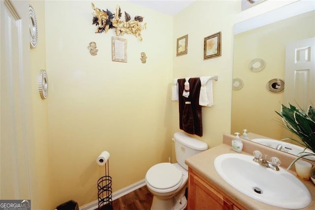 bathroom with wood finished floors, toilet, vanity, and baseboards