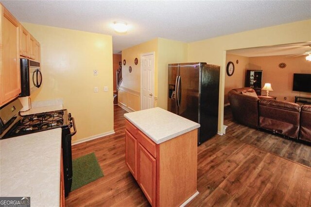 kitchen with stainless steel fridge, gas range oven, black microwave, dark wood-type flooring, and open floor plan