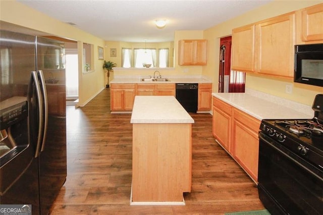 kitchen with black appliances, a sink, and light brown cabinetry