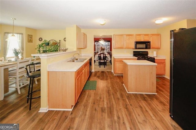 kitchen with black appliances, a sink, light countertops, and light brown cabinetry