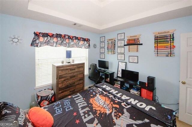 bedroom with an office area and a raised ceiling