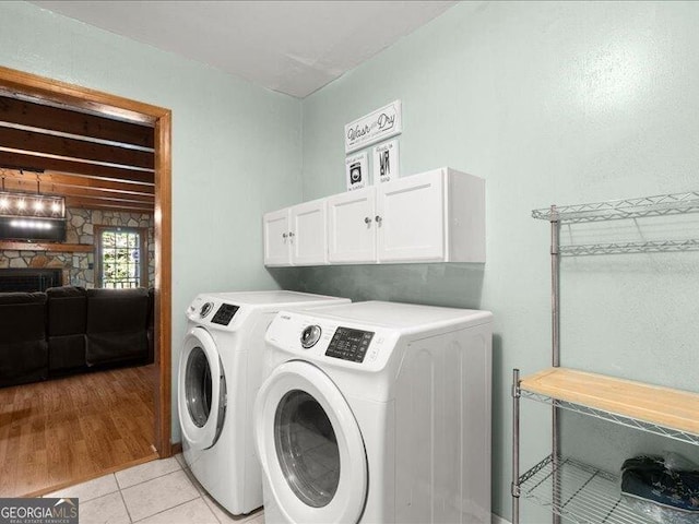 665 Mcclain Mountain Rd, Jasper, GA 30143 - washroom featuring cabinet space, separate washer and dryer, a stone fireplace, and light tile patterned floors