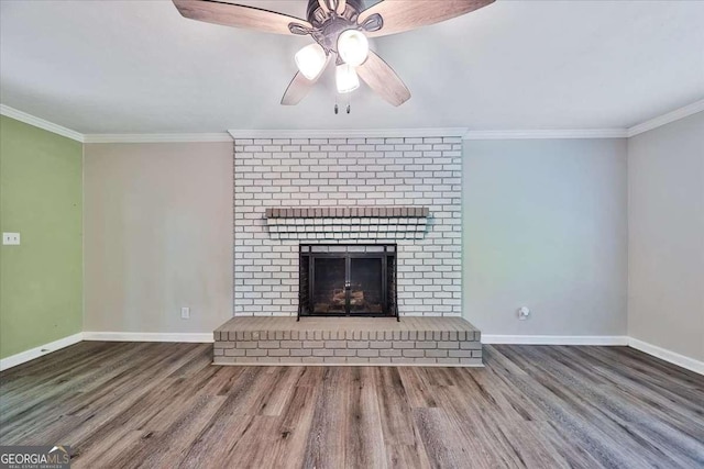 unfurnished living room with wood finished floors, baseboards, ornamental molding, a fireplace, and a ceiling fan