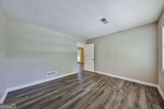 spare room with dark wood-style floors, baseboards, and a textured ceiling