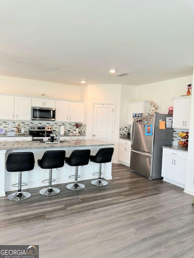 189 Bentwater Way, Hoschton, GA 30548 - kitchen with appliances with stainless steel finishes, decorative backsplash, a breakfast bar area, and recessed lighting