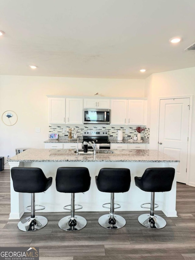 189 Bentwater Way, Hoschton, GA 30548 - kitchen with stainless steel appliances, light stone countertops, a breakfast bar area, and recessed lighting