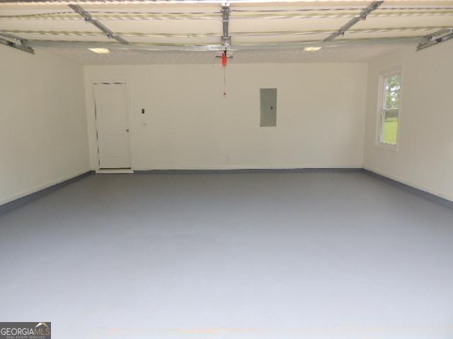 garage featuring electric panel and baseboards