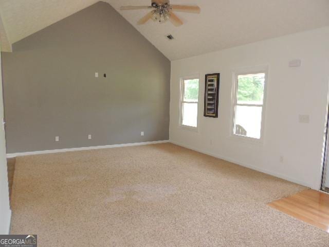empty room with a ceiling fan, vaulted ceiling, light carpet, and baseboards