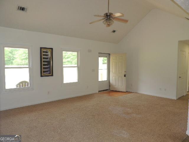 unfurnished room featuring light carpet, ceiling fan, high vaulted ceiling, and baseboards
