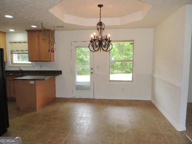 kitchen with dark countertops, a peninsula, a chandelier, plenty of natural light, and recessed lighting