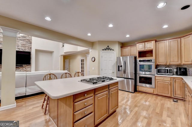 3565 Hickory Branch Trl, Suwanee, GA 30024 - kitchen featuring stainless steel appliances, a breakfast bar area, a kitchen island, light countertops, and light wood-style floors