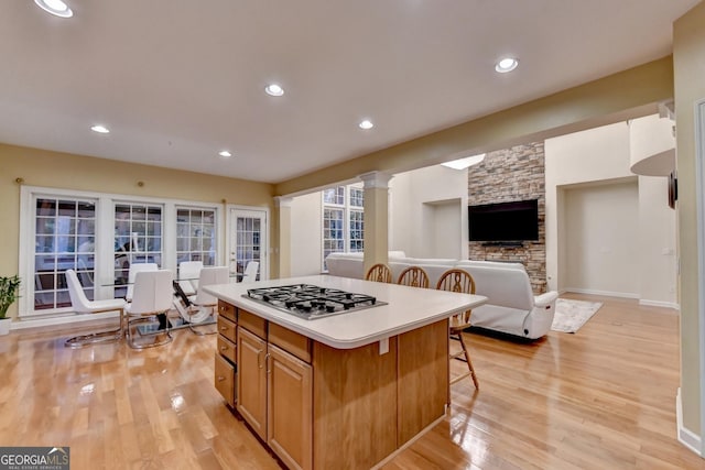 3565 Hickory Branch Trl, Suwanee, GA 30024 - kitchen featuring stainless steel gas cooktop, light wood-style floors, a breakfast bar, a center island, and light countertops