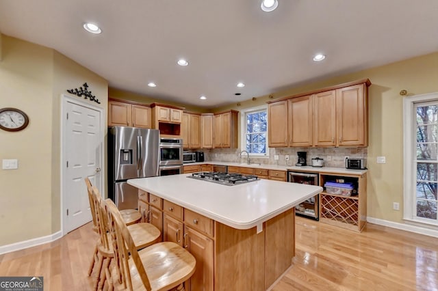 3565 Hickory Branch Trl, Suwanee, GA 30024 - kitchen featuring appliances with stainless steel finishes, beverage cooler, a kitchen breakfast bar, tasteful backsplash, and light wood-style flooring