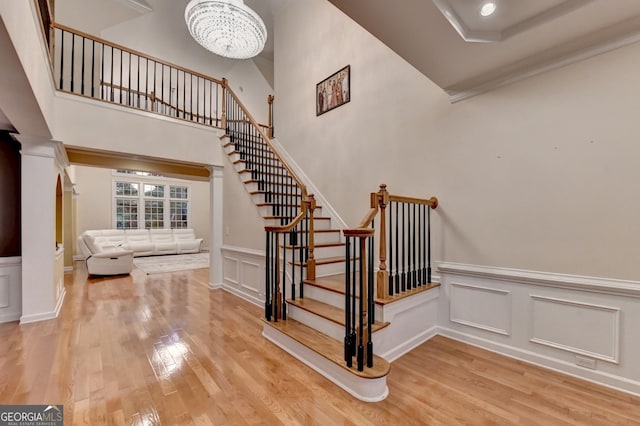 3565 Hickory Branch Trl, Suwanee, GA 30024 - stairway featuring wood finished floors, a decorative wall, a chandelier, a wainscoted wall, and crown molding