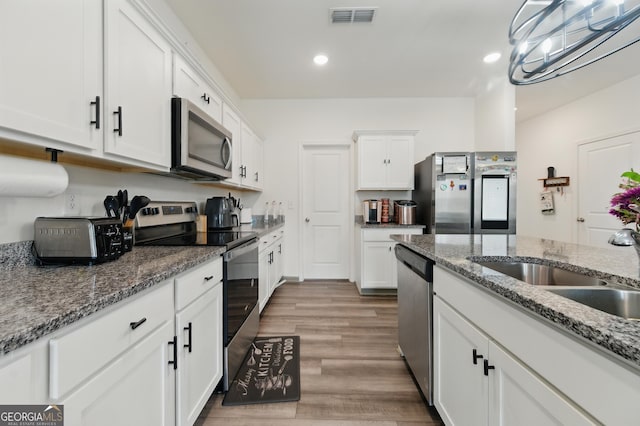 55 Knightsbridge Ln, Winder, GA 30680 - kitchen featuring stainless steel appliances, white cabinetry, wood finished floors, a sink, and recessed lighting