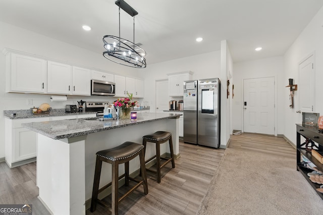 55 Knightsbridge Ln, Winder, GA 30680 - kitchen featuring appliances with stainless steel finishes, white cabinets, light wood-type flooring, a kitchen breakfast bar, and recessed lighting