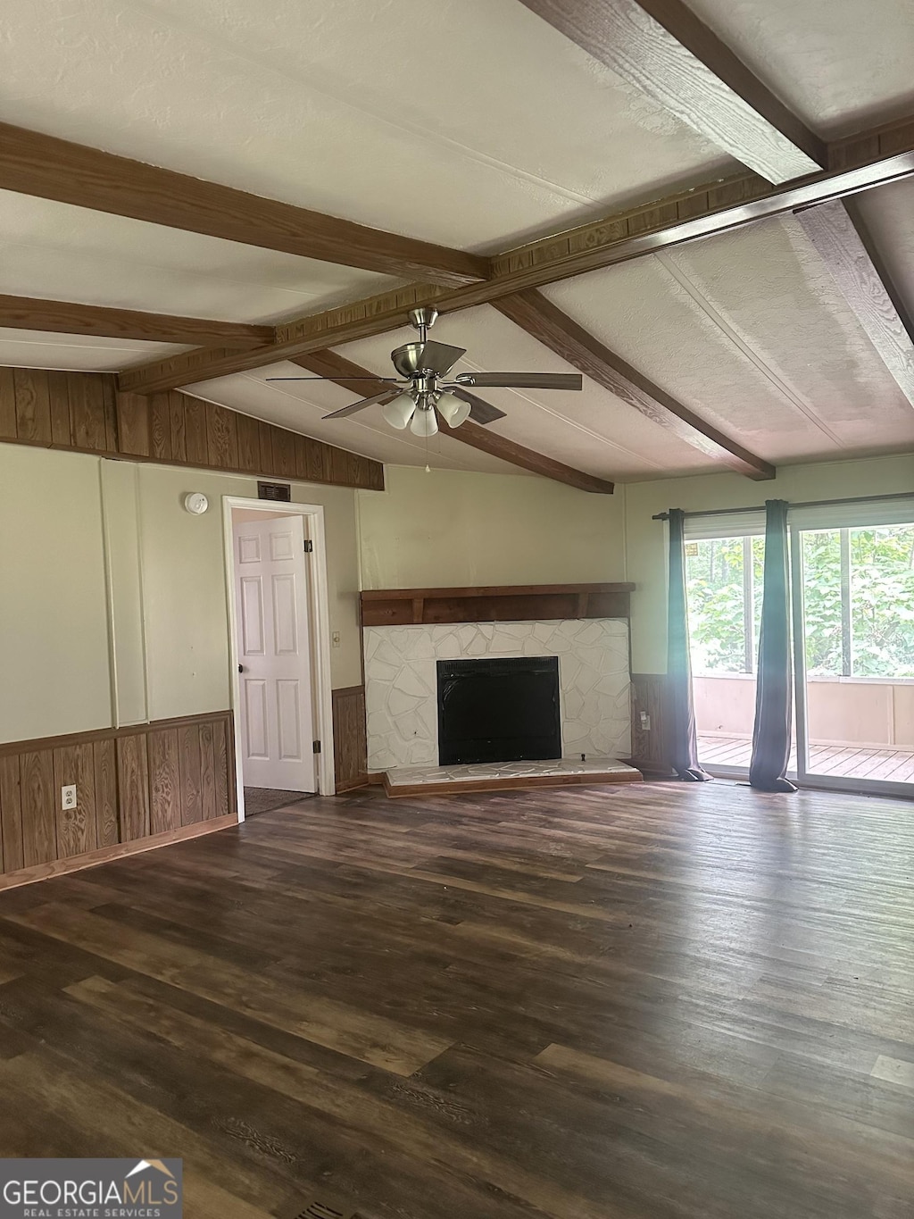 710 Seals Rd, Dallas, GA 30157 - unfurnished living room featuring ceiling fan, a wainscoted wall, wood finished floors, a fireplace, and wooden walls