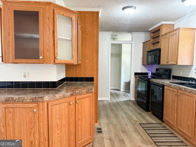 140 Holiday Rd, Franklin, GA 30217 - kitchen featuring black appliances, light wood-style flooring, dark countertops, glass insert cabinets, and a textured ceiling