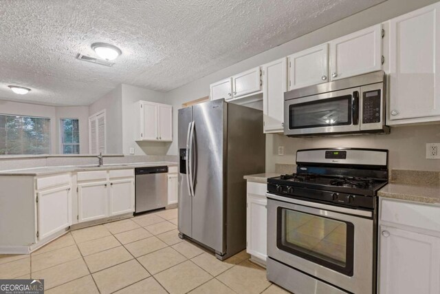 2907 Oakvale Falls Dr, Decatur, GA 30034 - kitchen with stainless steel appliances, a sink, white cabinets, light tile patterned floors, and a textured ceiling
