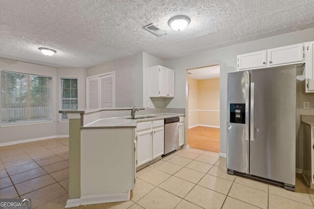 2907 Oakvale Falls Dr, Decatur, GA 30034 - kitchen featuring appliances with stainless steel finishes, a peninsula, a sink, light tile patterned flooring, and white cabinetry