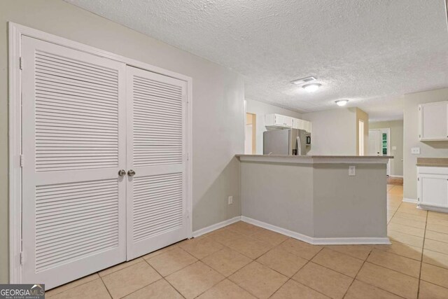 2907 Oakvale Falls Dr, Decatur, GA 30034 - kitchen featuring freestanding refrigerator, white cabinetry, light tile patterned floors, a peninsula, and baseboards