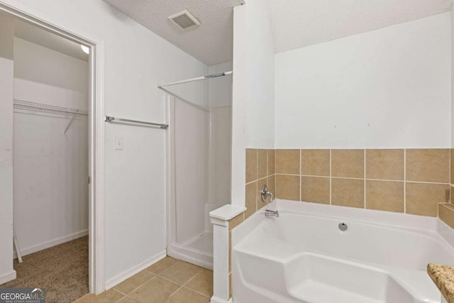 2907 Oakvale Falls Dr, Decatur, GA 30034 - bathroom with a spacious closet, a shower stall, a bath, a textured ceiling, and baseboards