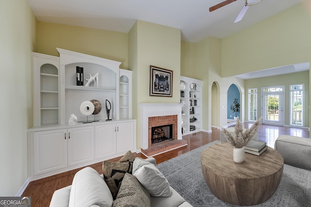 1151 Emperor Ln, Hoschton, GA 30548 - living room featuring ceiling fan, a fireplace, a high ceiling, and dark wood finished floors