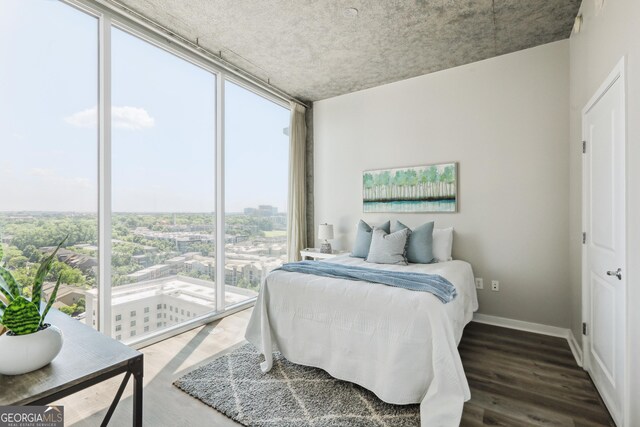 bedroom with expansive windows, wood finished floors, access to exterior, and baseboards