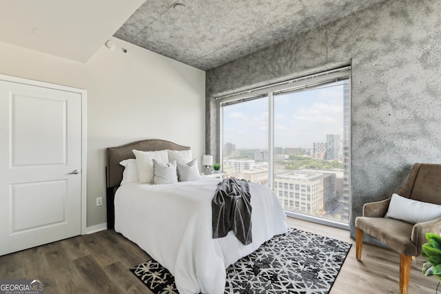 bedroom with access to outside, wood finished floors, and a view of city