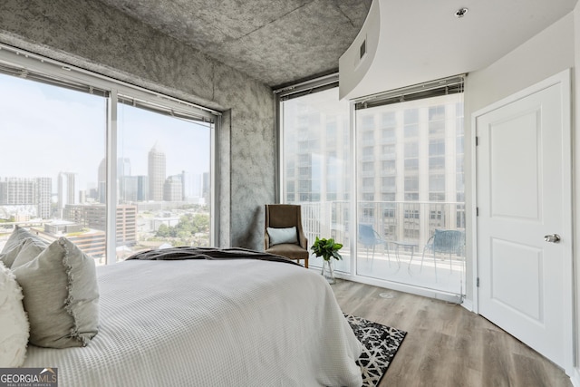 bedroom with access to exterior, a skyline view, and wood finished floors
