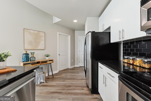 kitchen with appliances with stainless steel finishes, white cabinets, light wood finished floors, backsplash, and recessed lighting