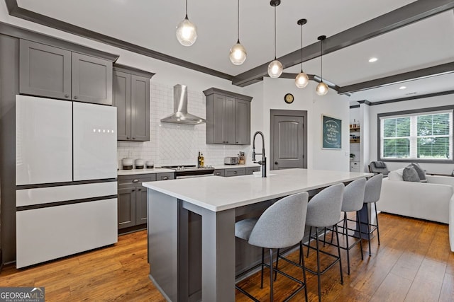 47 Wicklow Ct, Hoschton, GA 30548 - kitchen with freestanding refrigerator, wall chimney range hood, gray cabinetry, a breakfast bar area, and decorative backsplash