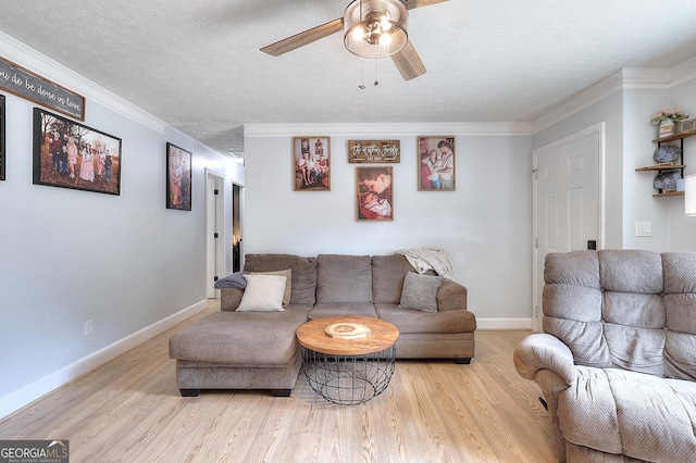 living room featuring ceiling fan, crown molding, wood finished floors, a textured ceiling, and baseboards