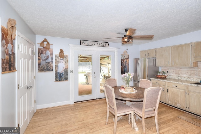 dining room featuring french doors, a textured ceiling, light wood-style flooring, a ceiling fan, and baseboards