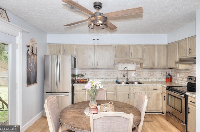 kitchen with appliances with stainless steel finishes, under cabinet range hood, a sink, light wood-type flooring, and a ceiling fan