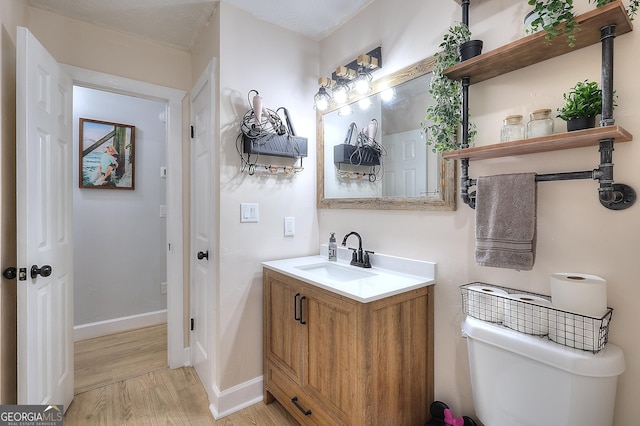 bathroom with wood finished floors, vanity, baseboards, and toilet