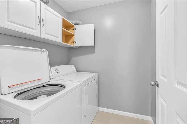 washroom featuring washer and clothes dryer, cabinet space, baseboards, and light tile patterned floors