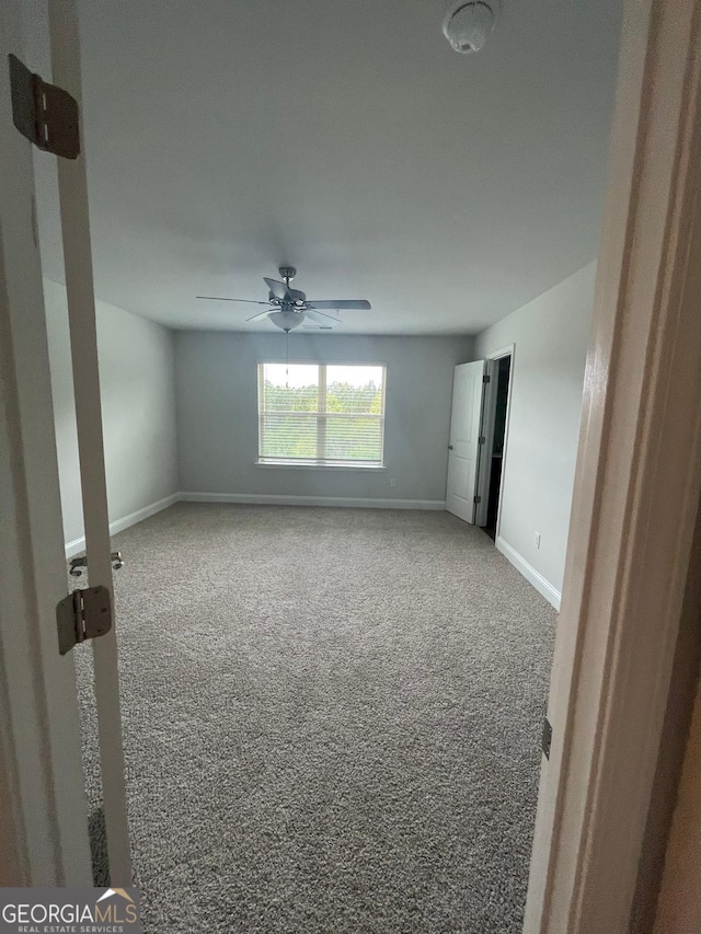 carpeted spare room with baseboards and ceiling fan