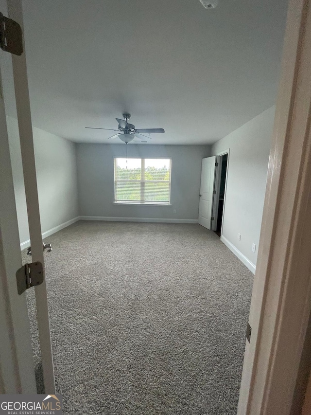 carpeted spare room with ceiling fan and baseboards