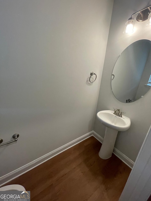 half bath featuring wood finished floors and baseboards