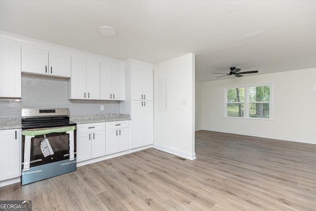 kitchen featuring stainless steel range with electric cooktop, light wood-style flooring, decorative backsplash, a ceiling fan, and baseboards